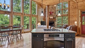 Una cocina amplia con una isla grande, paredes de madera y ventanas panorámicas con vistas al exterior.