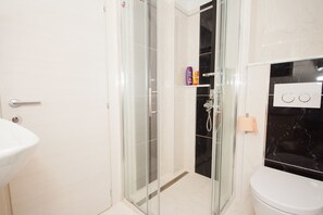 Ein Badezimmer mit Duschkabine, Waschbecken in Weiß und Toilette.