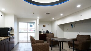 A clean, well-lit room with a coffee machine, seating area, and a view of the outside.