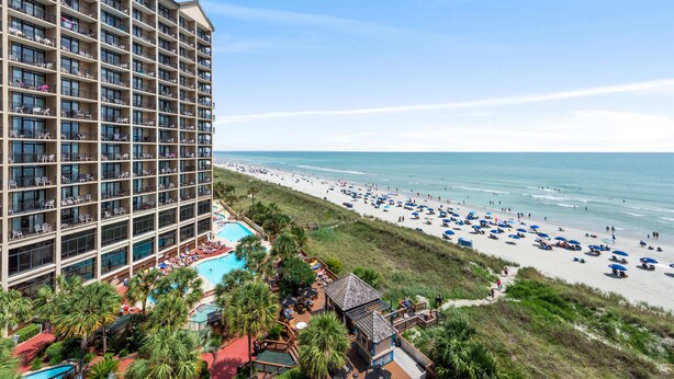 A high-rise hotel with a pool and beach view.