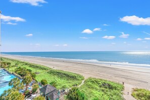 A beach resort with a swimming pool, beach access, and a view of the ocean.