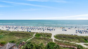 A beach with numerous umbrellas and people.