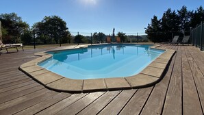 Una piscina rectangular con un deck de madera alrededor.