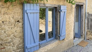 Un edificio rústico de piedra con puerta de madera y contraventanas azules.