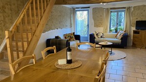 Una mesa de madera con sillas, una botella de vino y un posavasos.