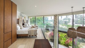 Un dormitorio moderno con una cama grande, armario de madera y un balcón con vistas a la vegetación.