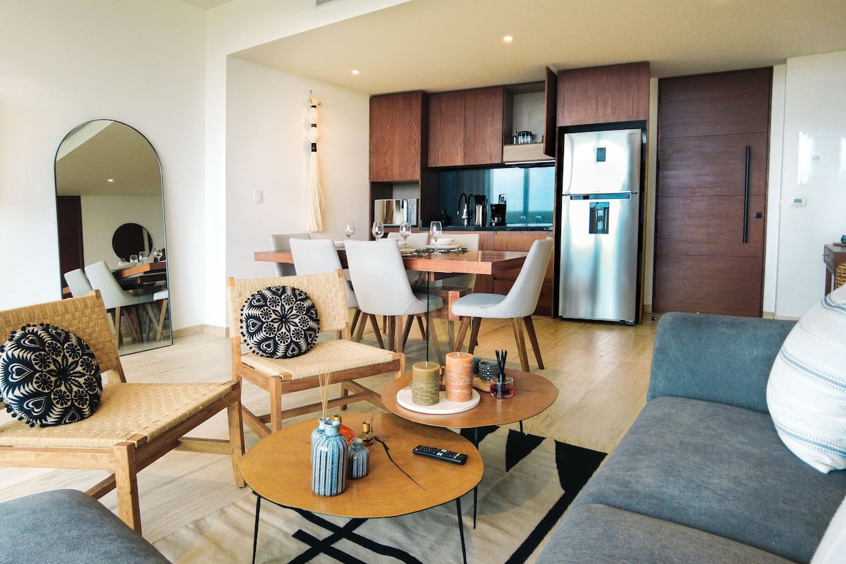 A modern living room with a sofa, chairs, a coffee table, and a dining area with a table and chairs.