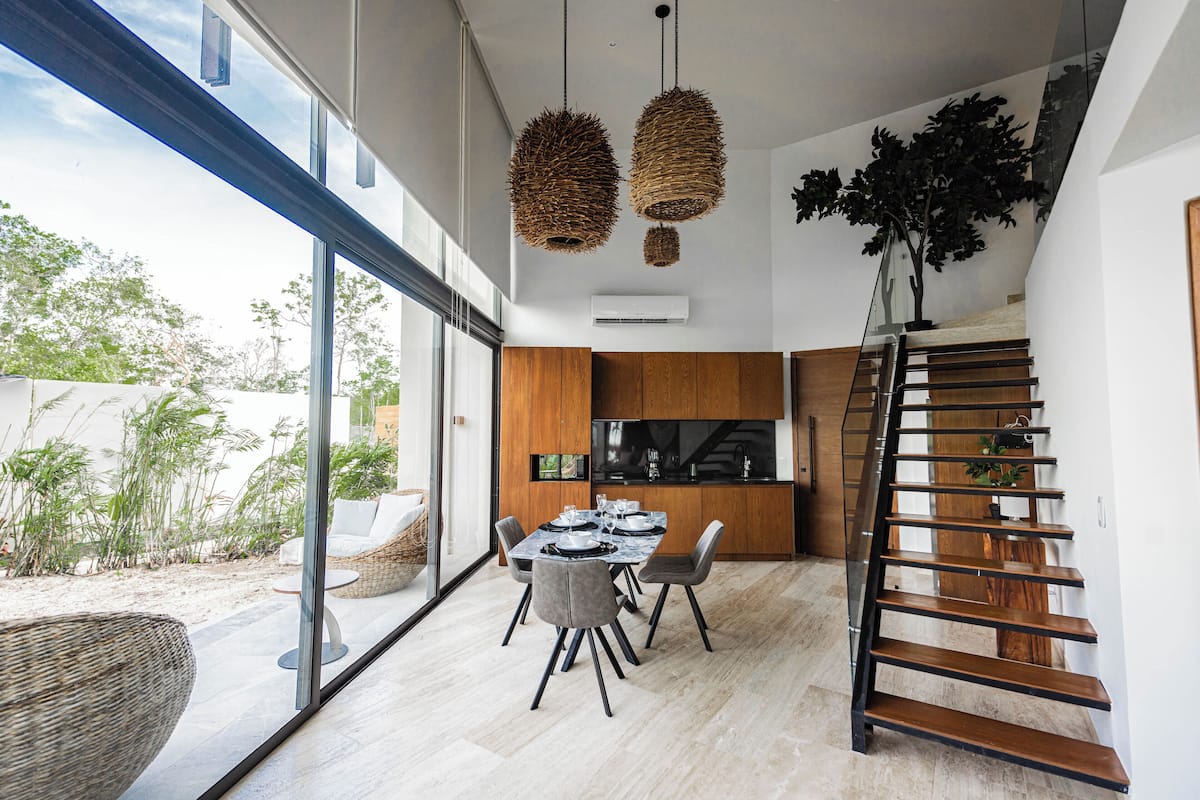 A modern dining area with a large table, chairs, and a view of the outdoors.