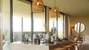 A modern kitchen with a central island, pendant lighting, and a view of the outdoors. - Mistiq Gardens (Tulum)