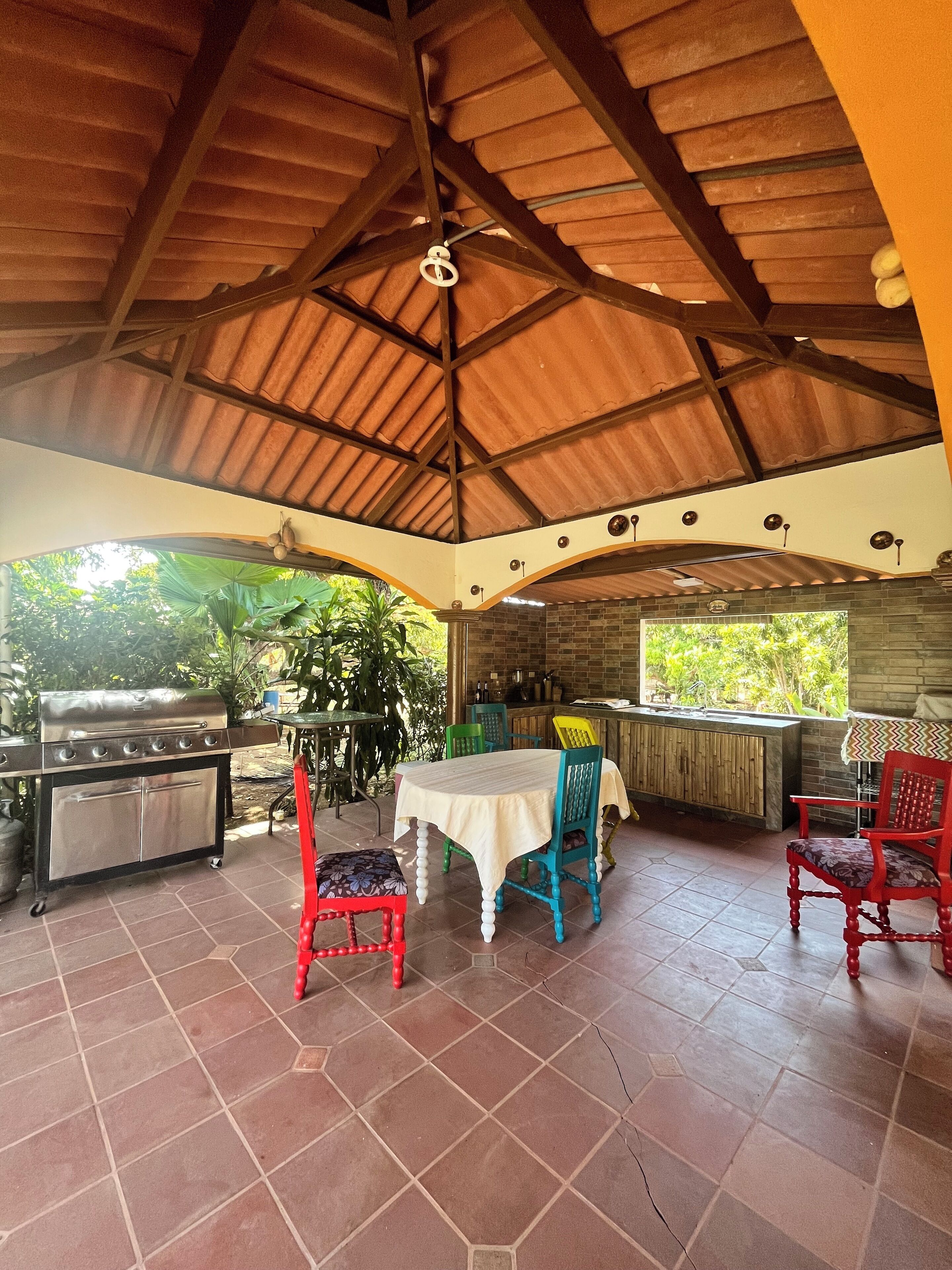 An outdoor patio with a grill, a table with chairs, and a brick wall. - Resting cabin with a unique garden, swimming pool and Panamanian traditions. (Guararé)