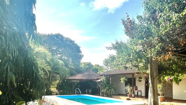 A backyard with a swimming pool, stone pathway, and various plants. - Resting cabin with a unique garden, swimming pool and Panamanian traditions. (Guararé)