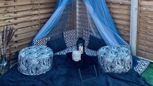 Une pièce avec un mur en bois, un dais bleu, des coussins à motifs et une statue.