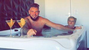 Un homme et une femme dans un jacuzzi, chacun tenant un verre.