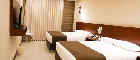 A hotel room with two beds, a TV, a desk, and a bathroom.