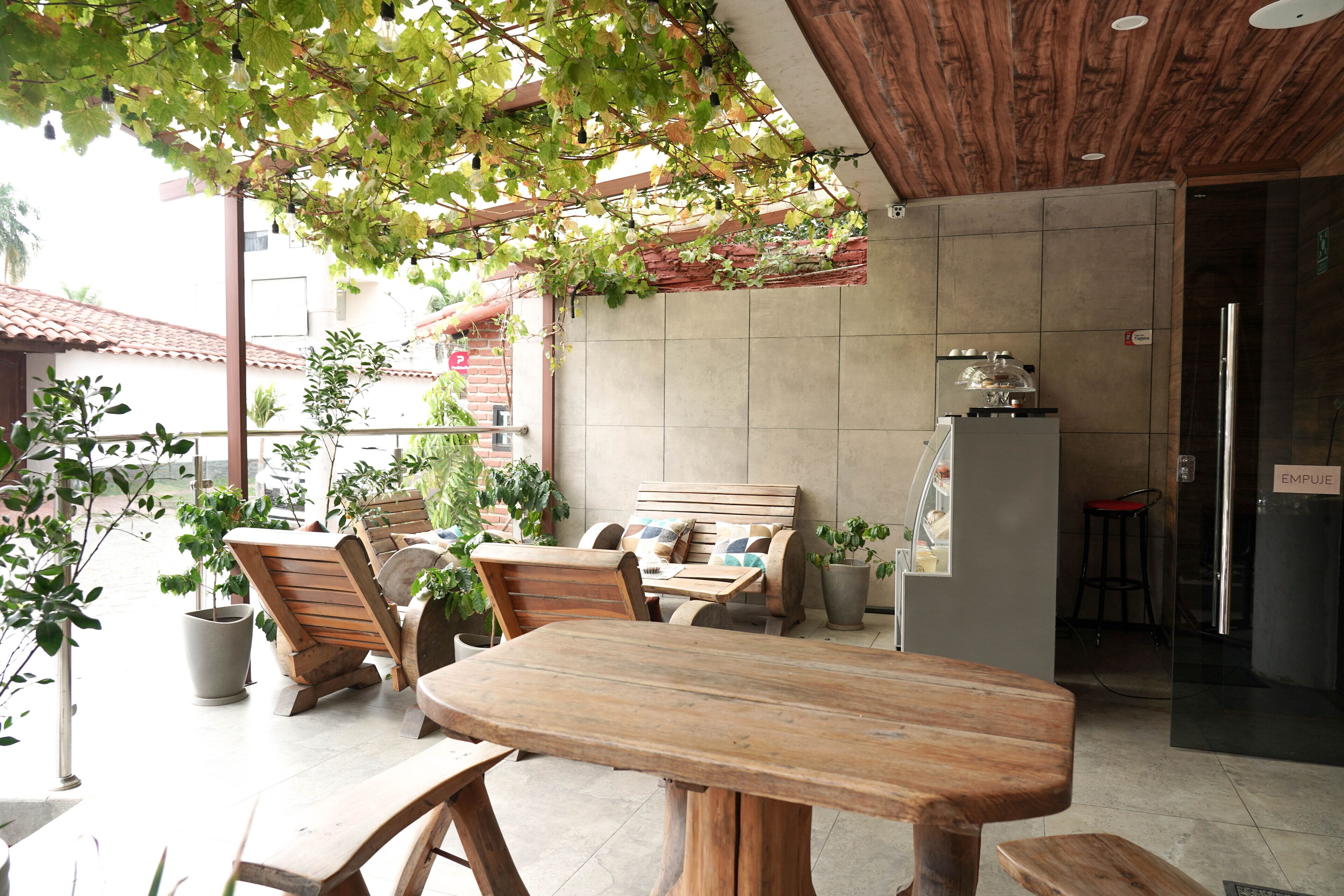 Een terras buiten met houten meubels, plantenbakken en een bakstenen muur.