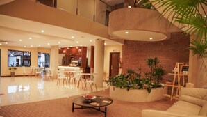 A spacious lobby with a brick accent wall, a seating area with a coffee table, and a view of the kitchen in the background. - Chairú Eco Hotel (Santa Cruz)