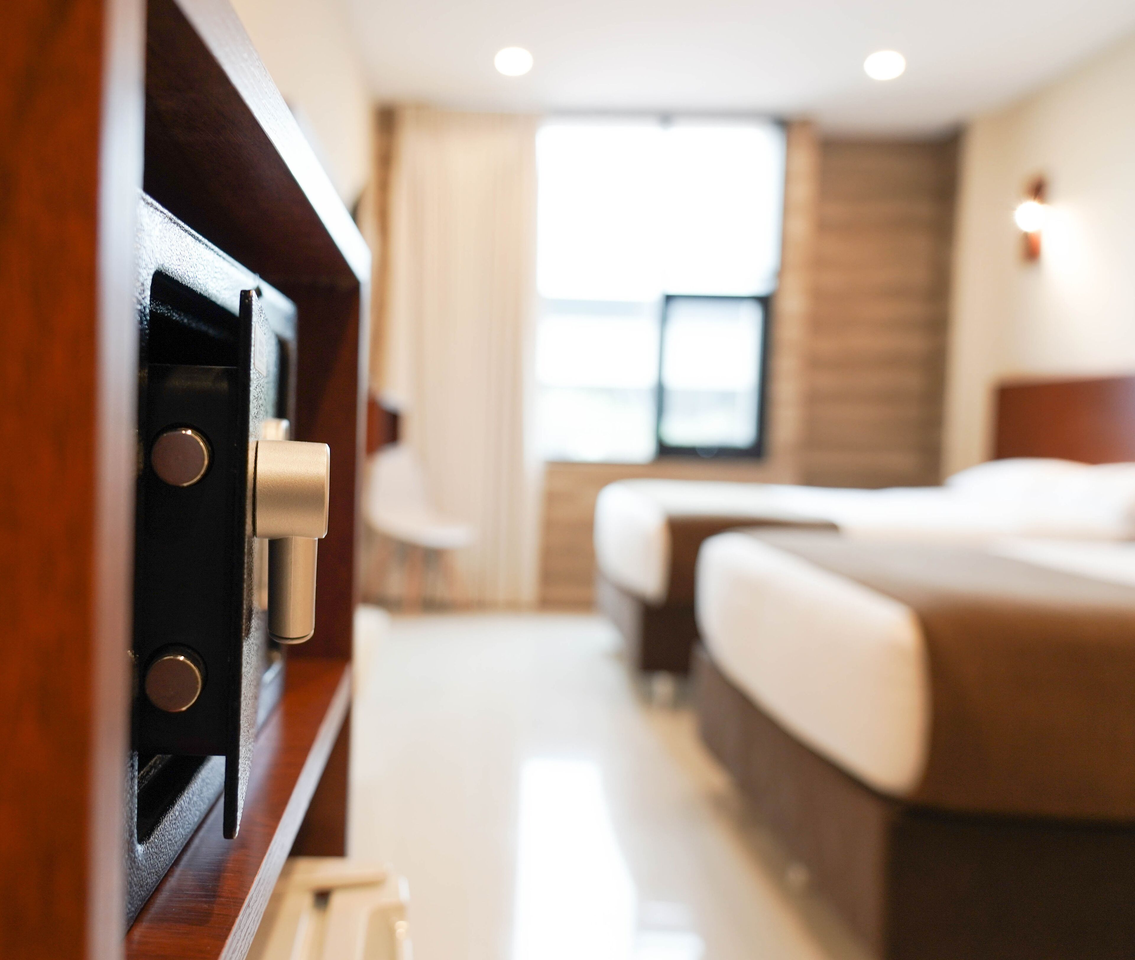 Una habitación de hotel con cama, mesita de noche y ventana con cortinas.