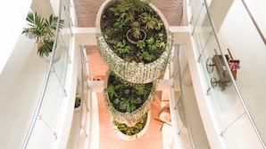 A multi-level atrium with a central planter containing various plants, surrounded by glass railings and a brick wall. - Chairú Eco Hotel (Santa Cruz)
