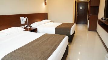 A hotel room with two beds, a desk, a chair, a TV, and a wardrobe.