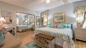 A bedroom with a bed, a dresser, a mirror, and a ceiling fan.