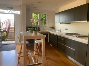 A modern kitchen with a central island, stainless steel cabinets, and a view to the outside.