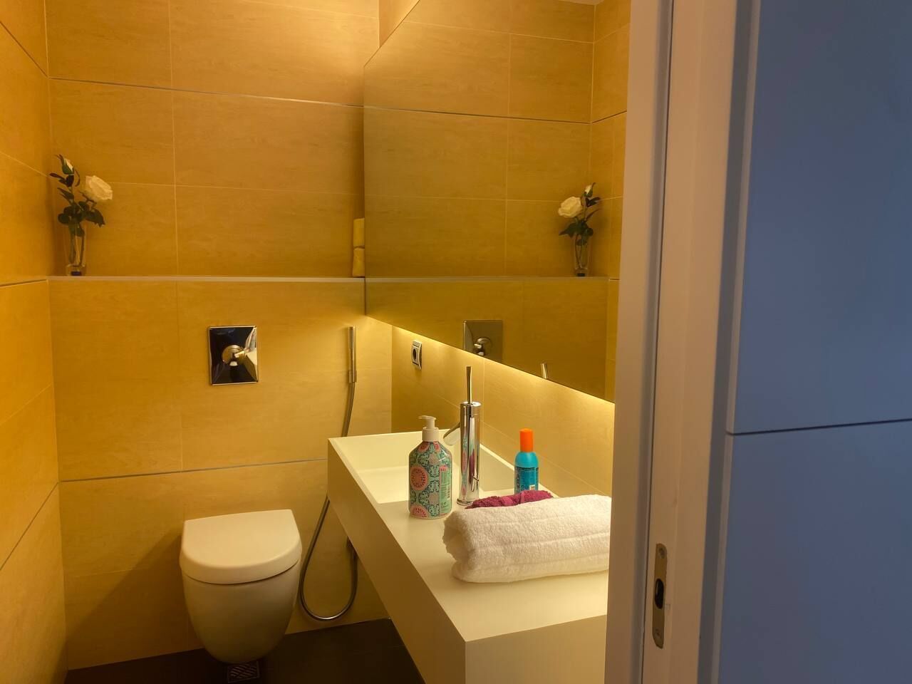 A bathroom with a white sink, a mirror, a white toilet, and a shower area.