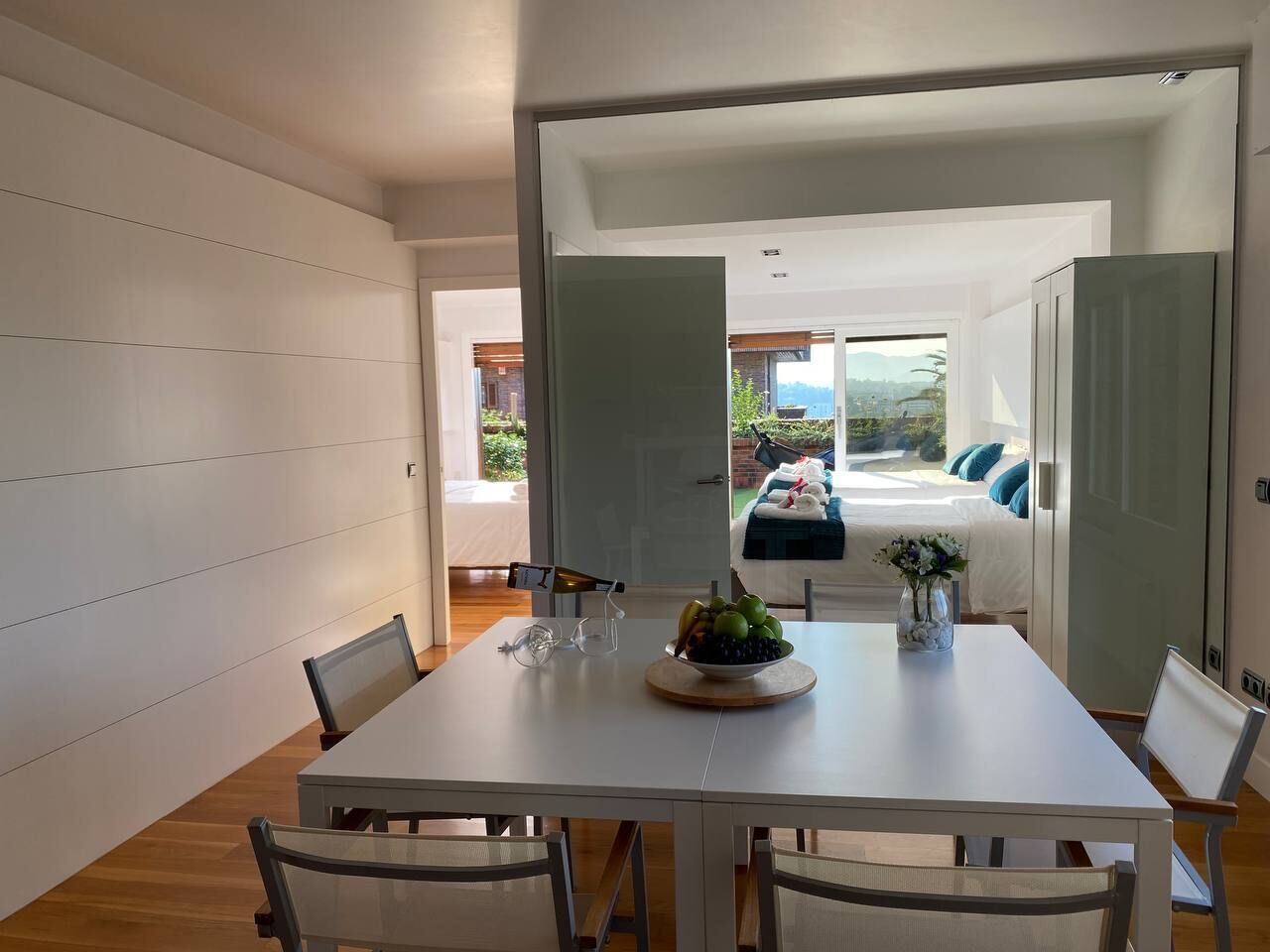 Un comedor moderno con una mesa blanca, sillas y un frutero.