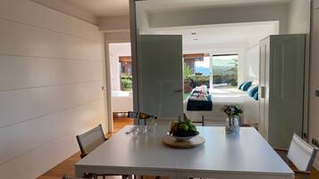 Un comedor moderno con una mesa blanca, sillas y un frutero.