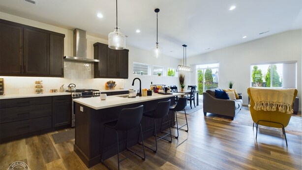 Een moderne keuken met donkere kastjes, een groot eiland en hanglampen.
