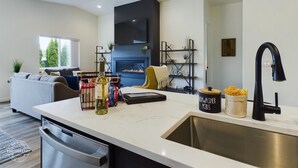 Een moderne keuken met een centraal eiland, roestvrijstalen apparatuur en een zwarte achterwand.