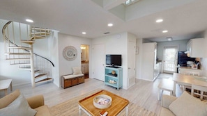 Stylish living space with a central spiral staircase, flat-screen TV, and cozy seating area.