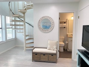 Experience a spacious room with a spiral staircase, comfortable seating area, and a television for relaxation.