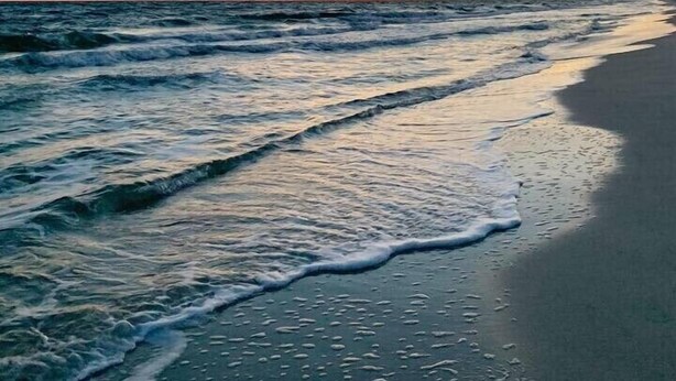 Ein Strand mit Wellen und blauem Himmel.