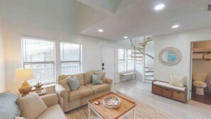 Ein großzügiges Wohnzimmer mit Sofa, Couchtisch und einer Treppe, die in ein Obergeschoss führt.
