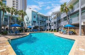 Relax by the resort's central pool surrounded by lounge chairs and umbrellas.