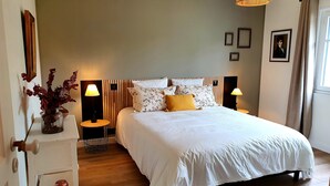 A neatly arranged bedroom with a large bed, two bedside tables with lamps, a wooden nightstand, and a vase with dried flowers. - The calm, the charm, the Maison du Menez: "the place to be" (La Forêt-Fouesnant)