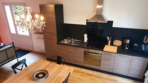 A modern kitchen with a wooden dining table, black chairs, and a chandelier. - The calm, the charm, the Maison du Menez: "the place to be" (La Forêt-Fouesnant)