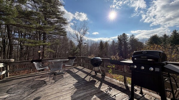 A wooden deck with a grill and outdoor seating.