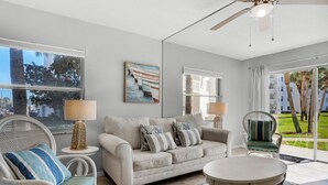 Una sala de estar moderna con un sofá, sillones, una mesa de centro y un cuadro en la pared.