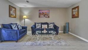 A living room with two blue sofas, a coffee table, and a lamp.