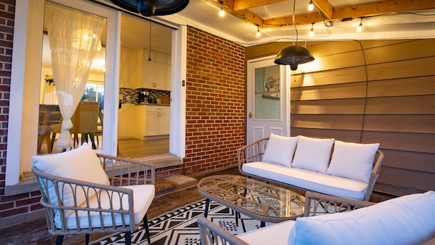 An outdoor patio with wicker furniture, a glass table, and a brick wall. - Green Door Getaway — family-friendly 4BR, 10 minutes to New River Gorge (Oak Hill)