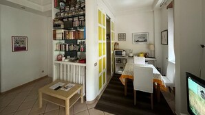 Een compact woongedeelte met een boekenkast, een eethoek en een televisie.