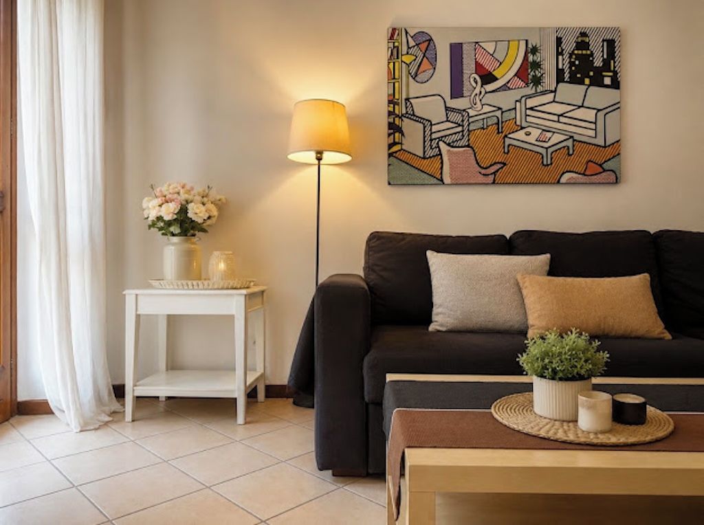 Un soggiorno con un divano, un tavolino, una lampada e un quadro appeso al muro.