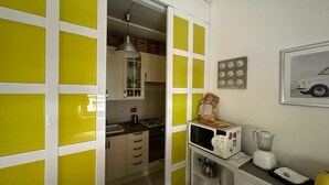 Een keuken met een magnetron, blender en kastjes.
