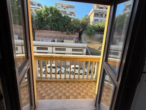 A balcony with a view of parked cars and buildings.