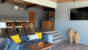 Una sala de estar moderna con un sofá, una mesa de centro y una zona de comedor con muebles de madera.