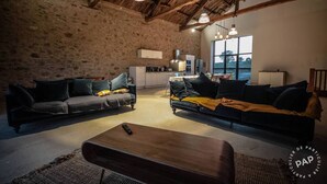 A rustic interior with two sofas, a coffee table, and a kitchen in the background. - Mas des Pêcheurs (Le Ségur)