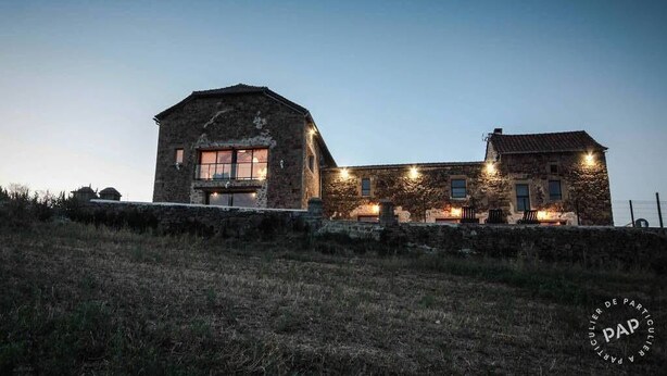 A stone building with a large window and a smaller window on the side, surrounded by a stone wall and a grassy area. - Mas des Pêcheurs (Le Ségur)