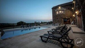 A poolside area with lounge chairs and a stone building with lights. - Mas des Pêcheurs (Le Ségur)