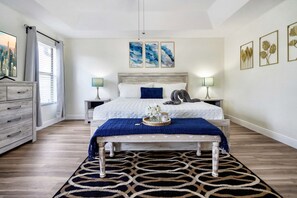 Un dormitorio con cama, mesitas de noche, cómoda y obras de arte en las paredes.